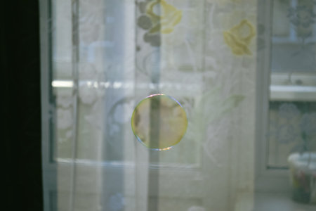 Perfectly round transparent soap bubble against the background of white curtains with a pattern