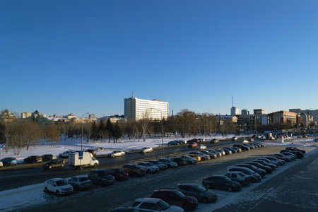 Parking with many cars next to the highway and against the backdrop of the panorama of the city in winter and the blue skyのeditorial素材