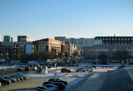 Close-up of the city center with many buildings. Parking lot with many cars next to busy highway and blue skyのeditorial素材