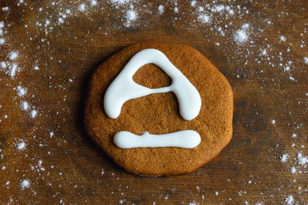 One sweet cookie, covered with white icing in the shape of the letter A, lies on an old board...