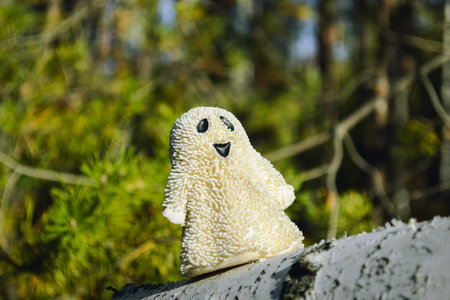 A smiling ghost toy close-up stands on a birch bark in the forest and sunlitの写真素材