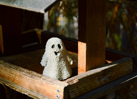 A small toy ghost stands in a bird feeder in the forestの写真素材