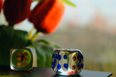 Transparent dice on the background of a window and a bouquet of red peonies