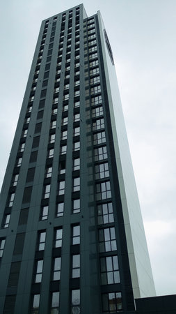 A view from below of a tall multi-storey building against a glowy sky