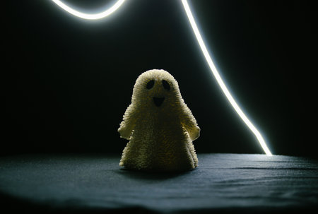 A toy smiling ghost stands in the semi-darkness and a strip of light above itの写真素材