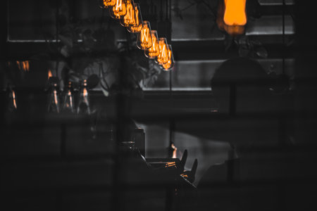 Moody Cafe Scene with Warm Edison Bulbs and Silhouetted Figureの写真素材