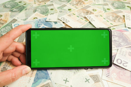 A green screen in his hand against a background of paper money. Space for your text.