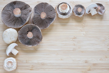 Whole and cut Agaricus mushrooms lie on the table. Mushrooms of different sizes. Background. A place...