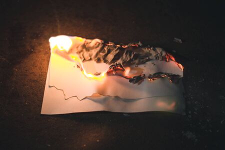 Charred sheet of white paper on dark backgroundの写真素材