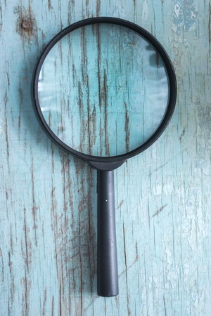 Magnifying glass on a blue wooden boardsの写真素材