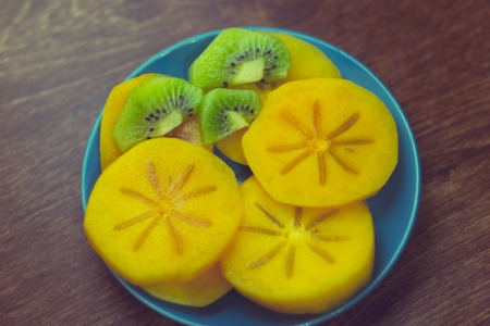 Persimmon on a plate on a wooden backgroundの写真素材