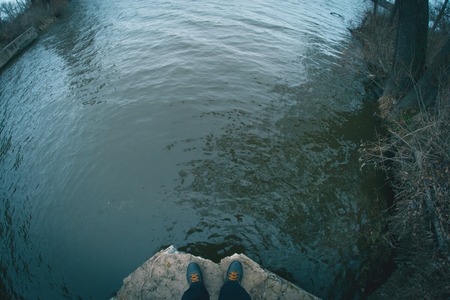 Legs on the edge of a concrete dam near the river.の写真素材