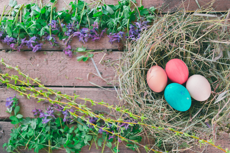 Multi-colored Easter eggs on a wooden background in the nestの写真素材