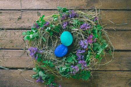 Multi-colored Easter eggs on a wooden background in the nestの写真素材