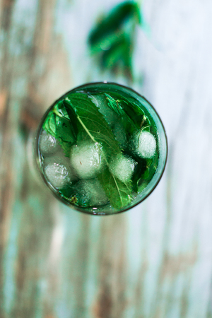 Glass with ice and mint leaves on a blue backgroundの写真素材