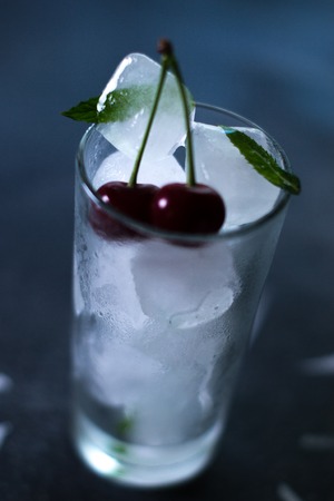 Natural ice in a glass with cherries on a black backgroundの写真素材