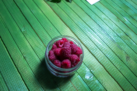 Fresh ripe raspberries on green wooden boards
