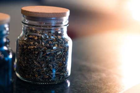 Different types of tea in glass jars on a blurred backgroundの写真素材
