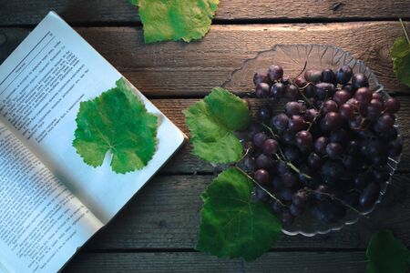 Autumn still life: Grapes with a book on a wooden backgroundの写真素材
