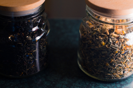 Different types of tea in glass jars on a blurred backgroundの写真素材