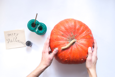 Male hands decorate a Halloween pumpkin on a white backgroundの写真素材