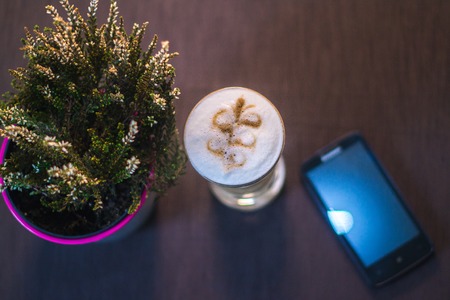 A cup of coffee, a smartphone in a cafe with a blurred background