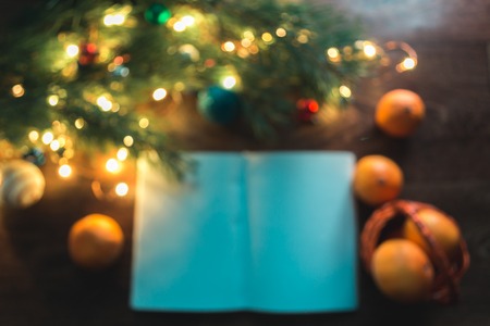 Open notebook on a wooden background with Christmas decorations in a blurred backgroundの写真素材