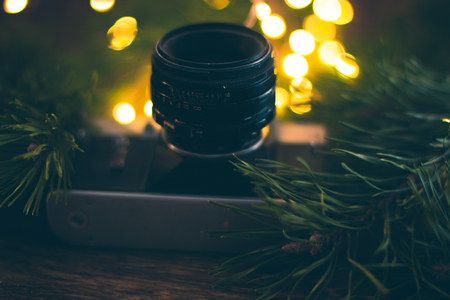 The old camera on a wooden background with Christmas tree branches and lightsの写真素材