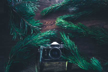 Old camera on a wooden background with Christmas tree branchesの写真素材