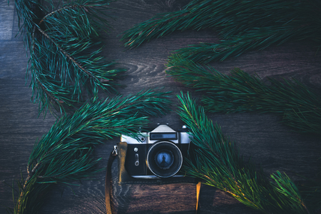 Old camera on a wooden background with Christmas tree branchesの写真素材