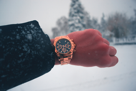 A man's hand with a gilded clock against a snowfall in the townの写真素材