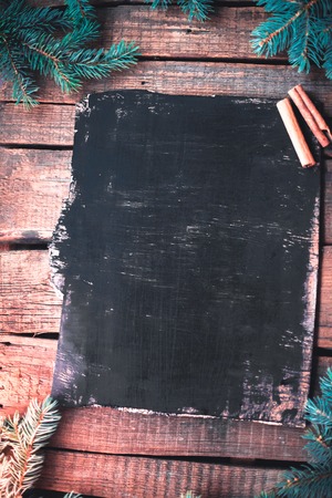 Black wooden board with Christmas tree branches and cinnamon sticksの写真素材