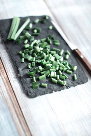 Sliced green stems on a black kitchen board.の写真素材