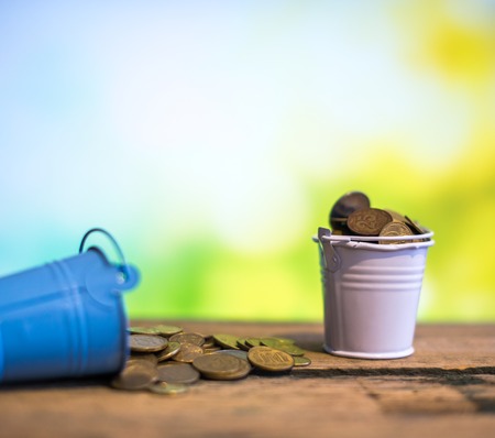 Two buckets of coins. One is upside down and the other is full. The concept of success.
