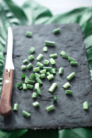 Sliced green stems on a black kitchen board.の写真素材