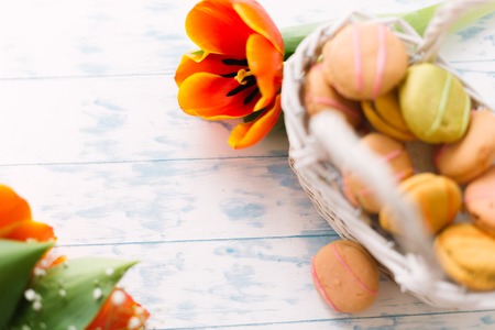 Blossoming tulips with macaroons on a light wooden background. Still life, spring concept.の写真素材
