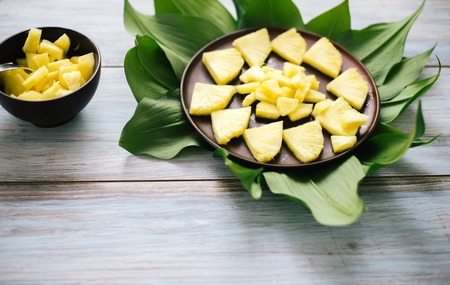 Sliced fresh pineapple in a bowl on the leaves.の写真素材