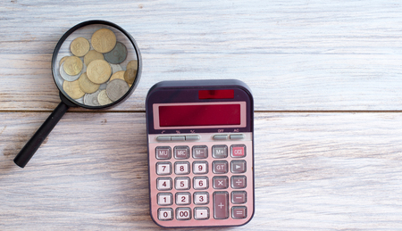 Magnifying glass and calculator on a wooden table with coins. Concept Accountant.の写真素材
