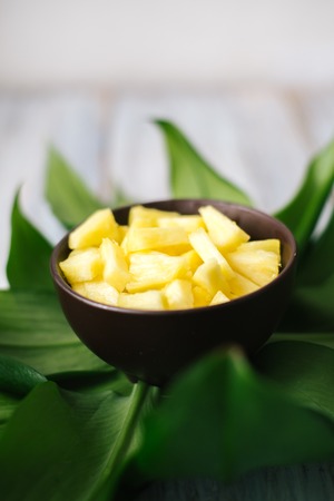 Sliced fresh pineapple in a bowl on the leaves.の写真素材