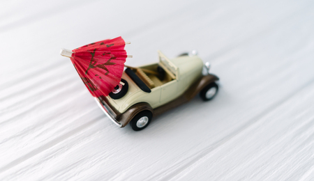 Toy small car on a white wooden background with an umbrella. Concept travel.の写真素材