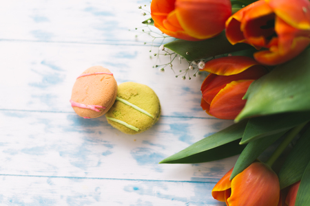 Blossoming tulips with macaroons on a light wooden background. Still life, spring concept.の写真素材