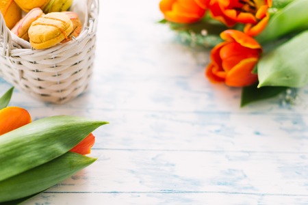 Blossoming tulips near a basket with macaroons.の写真素材