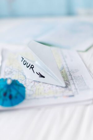 Paper airplane on the map with beach small umbrellas for a cocktail.の写真素材