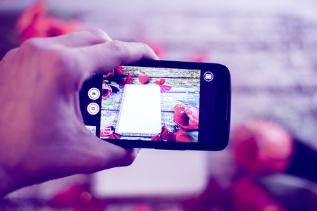 The hand holds the phone and photographs the still life of the tulips.の写真素材