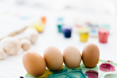 The process of painting Easter eggs still life on a white wooden background.の写真素材