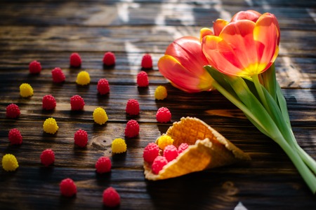Blossoming red tulips on a wooden background with sweetsの写真素材