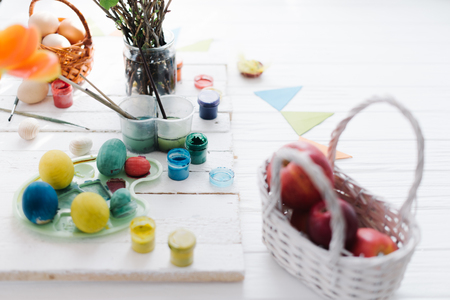 The process of painting Easter eggs still life on a white wooden background.の写真素材