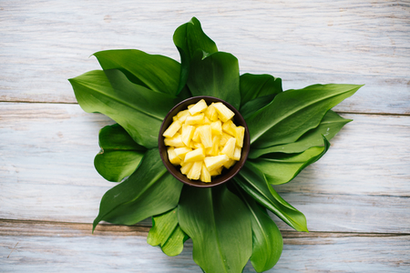 Sliced fresh pineapple in a bowl on the leaves.の写真素材