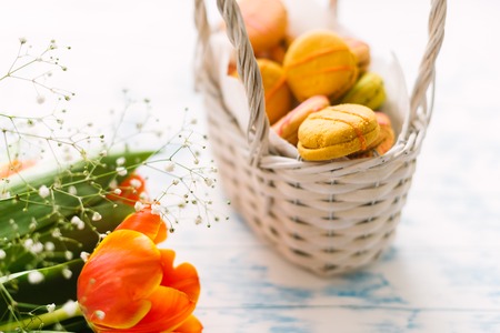 Blossoming tulips near a basket with macaroons.の写真素材