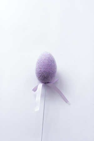 Violet easter egg on a stick on a white background.の写真素材